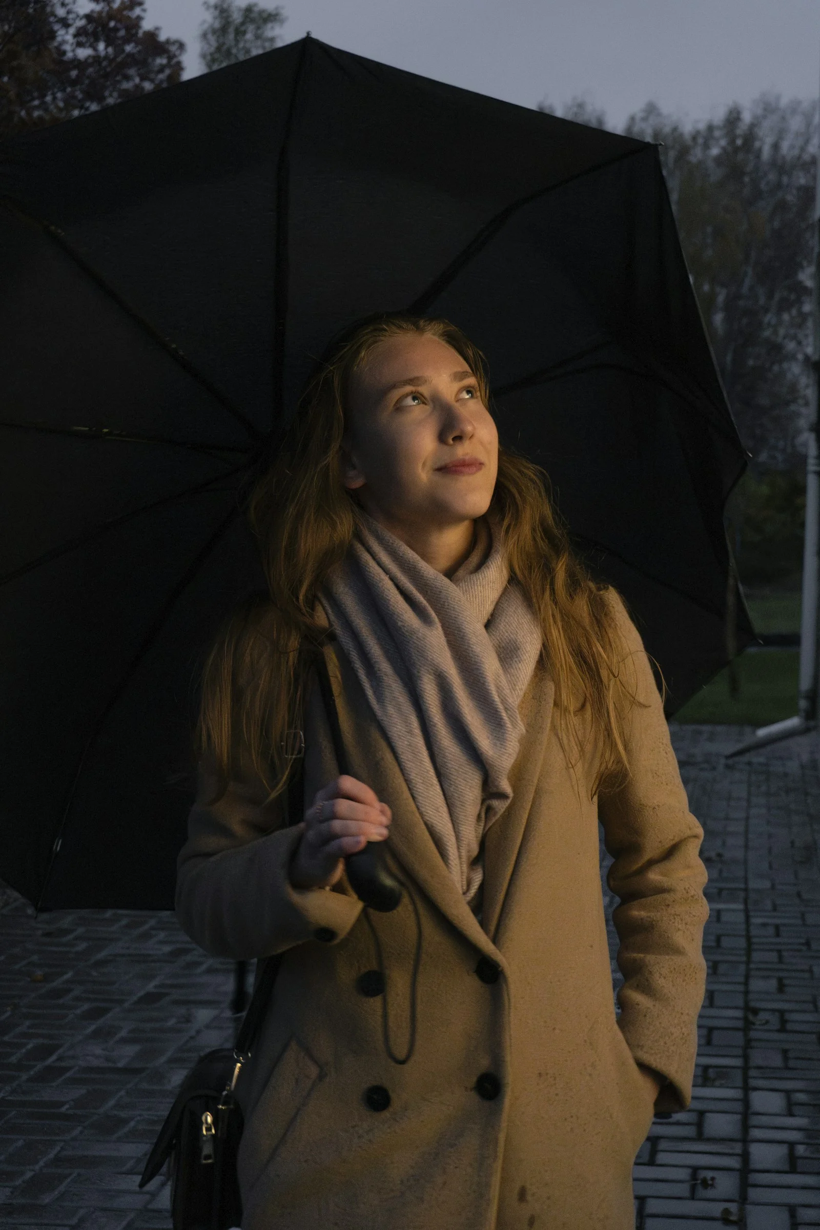 a woman holding a black umbrella on a sidewalk