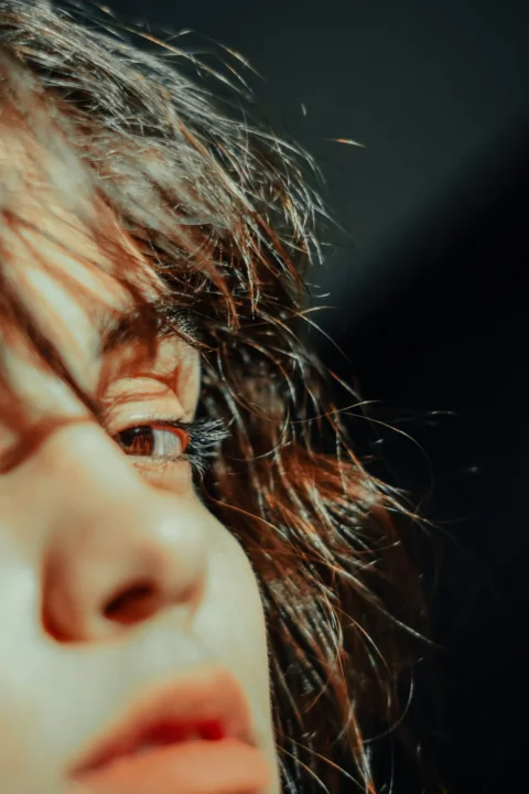 A close up of a woman's face with hair blowing in the wind
