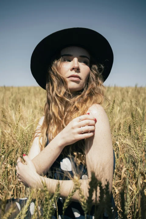 Woman in hat stands in a golden wheat field