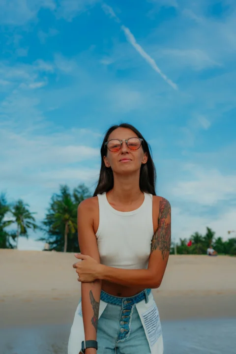 Woman poses on a beach with sunglasses