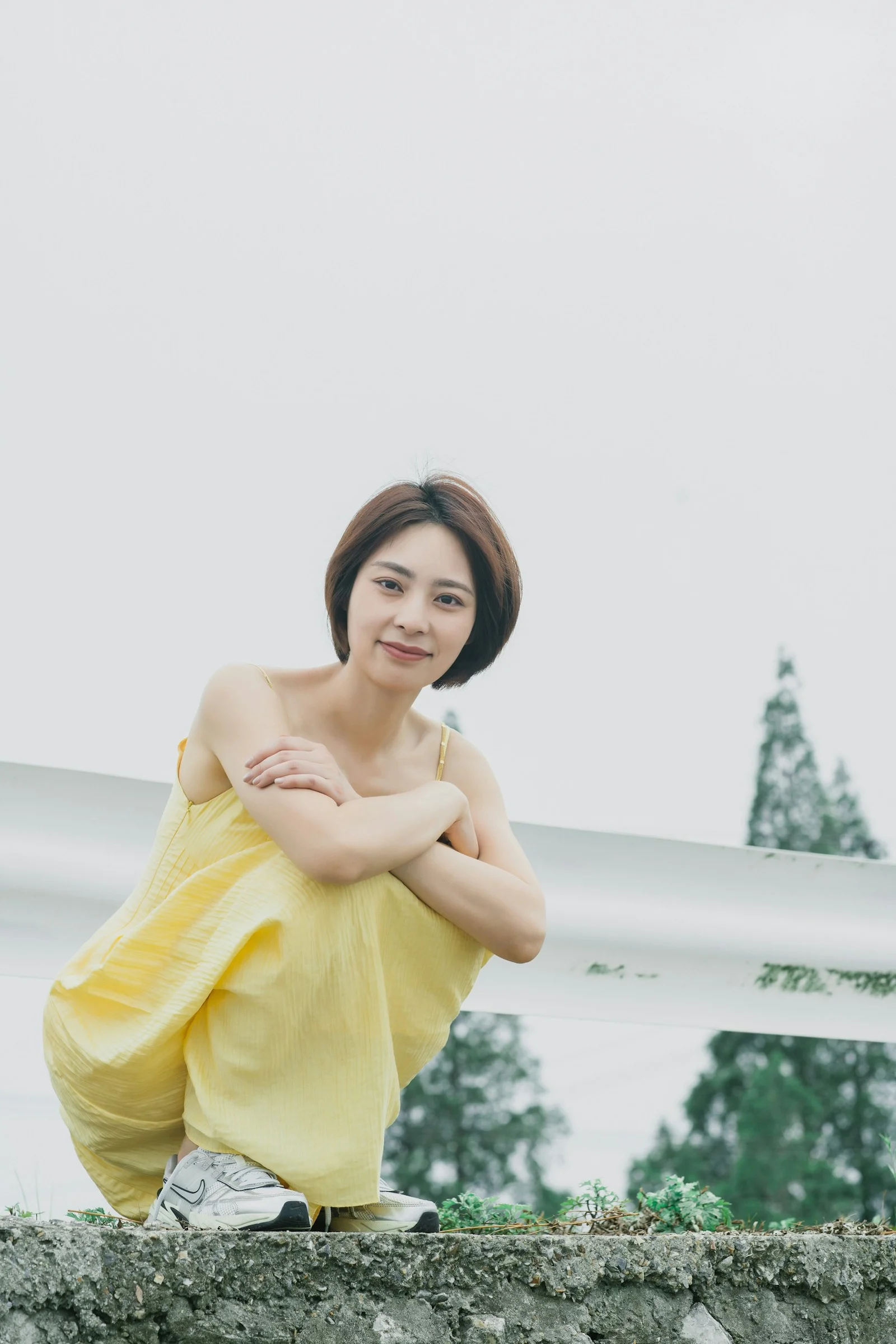 Woman in yellow dress poses cheerfully outdoors