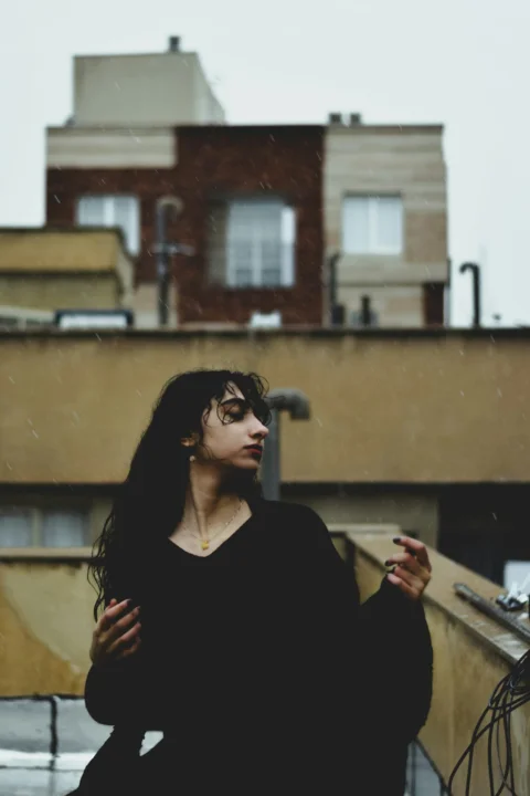 A woman standing on top of a roof next to a building