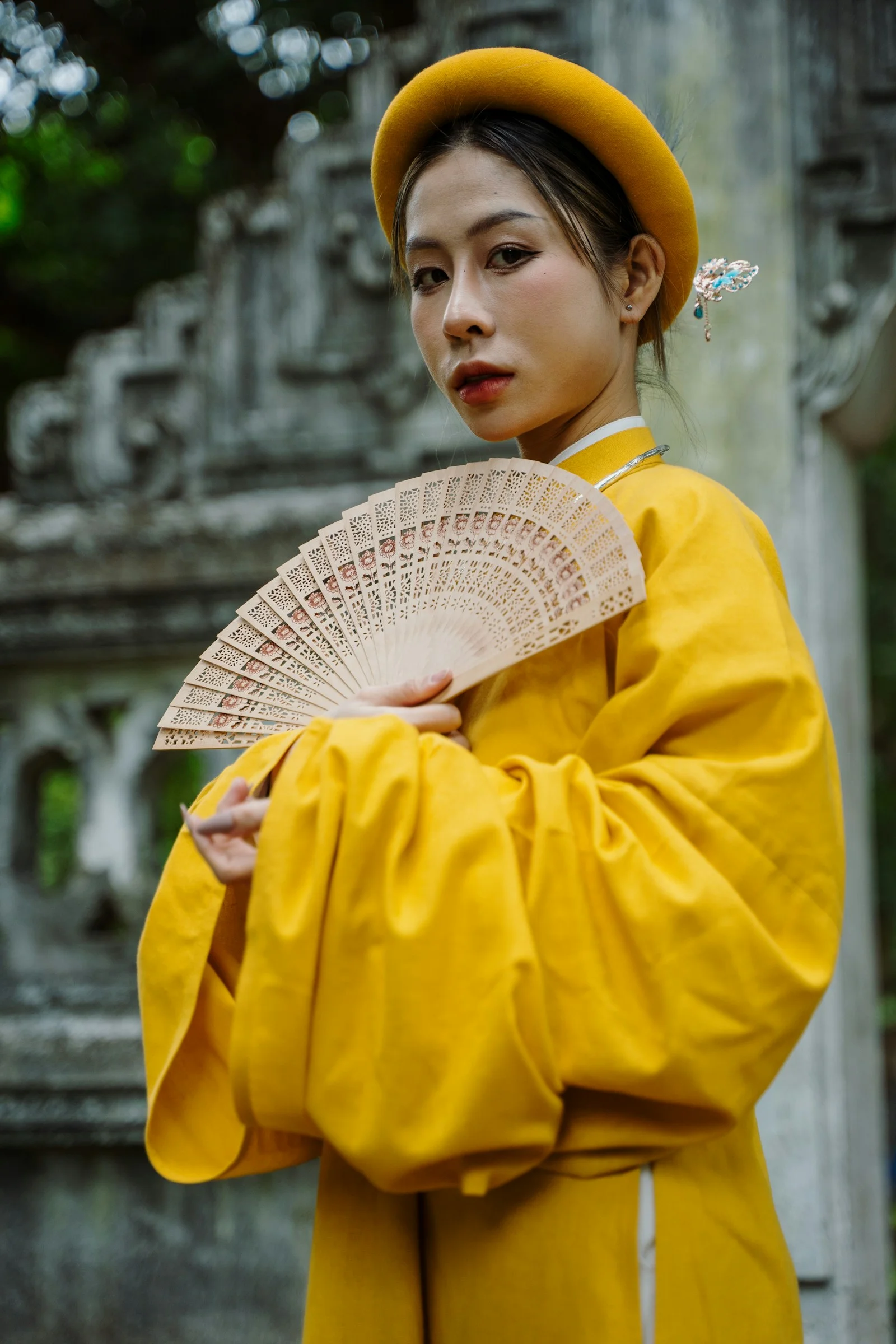 一位穿黄色服装、手持扇子的女性