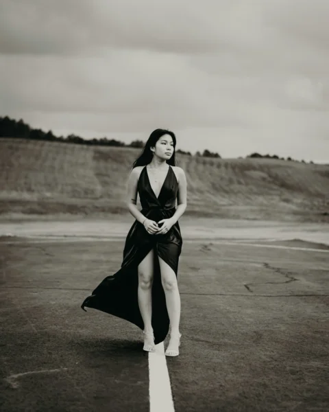 a woman in a black dress standing on a runway