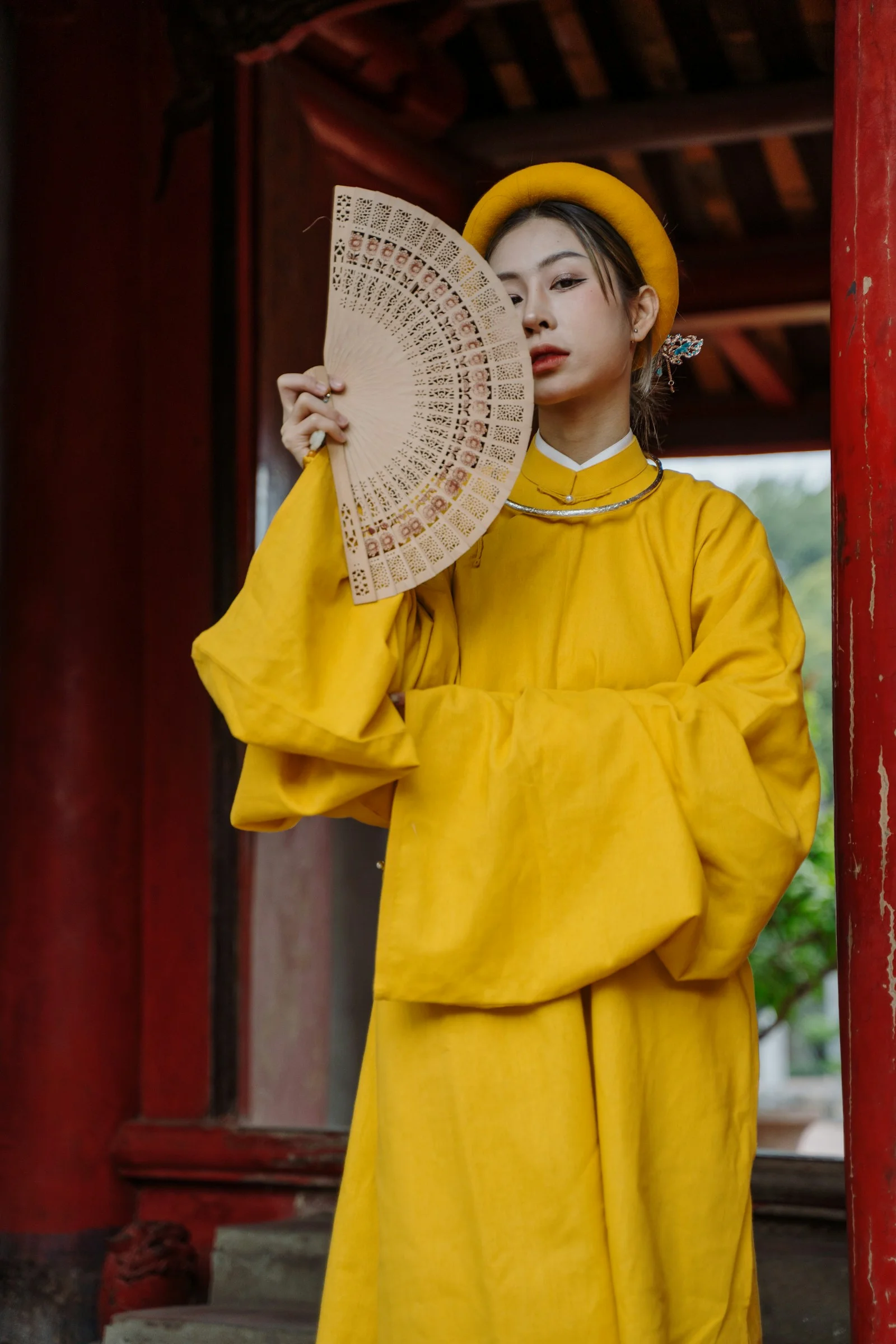 身穿黄色套装手持扇子的女子