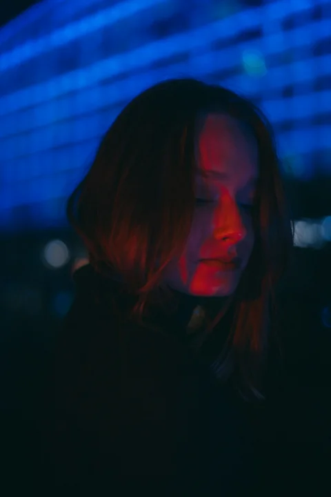 a woman standing in the dark looking at her cell phone