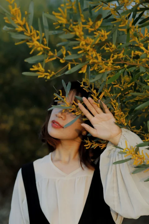 身穿黑白校服的女子手持黄色树叶