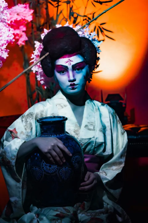 a person with a face paint holding a jar of food
