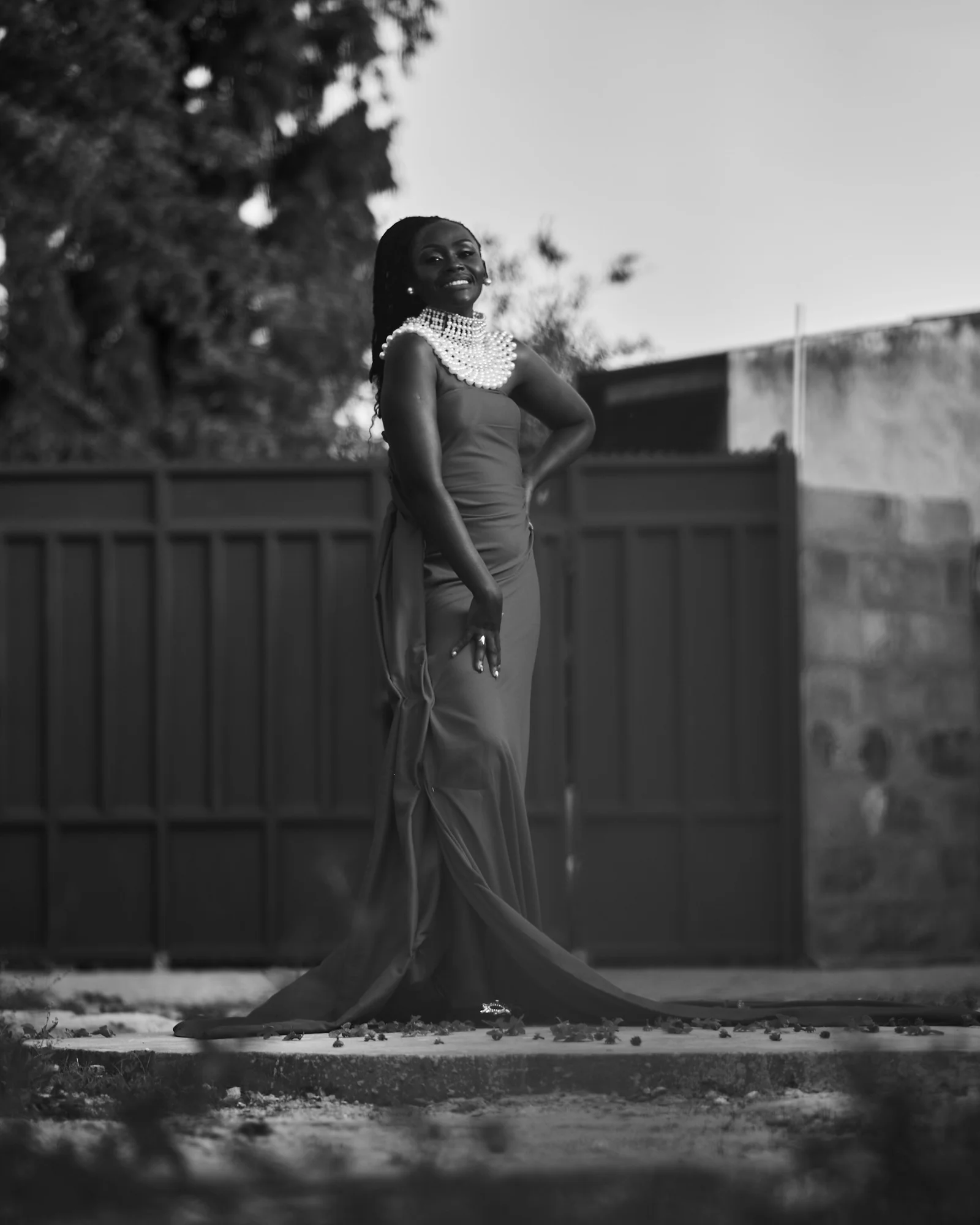a woman in a long dress standing in front of a fence
