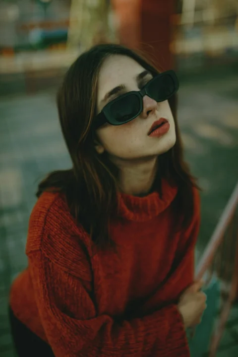 一位穿着红色毛衣、戴着黑色太阳镜的女子
