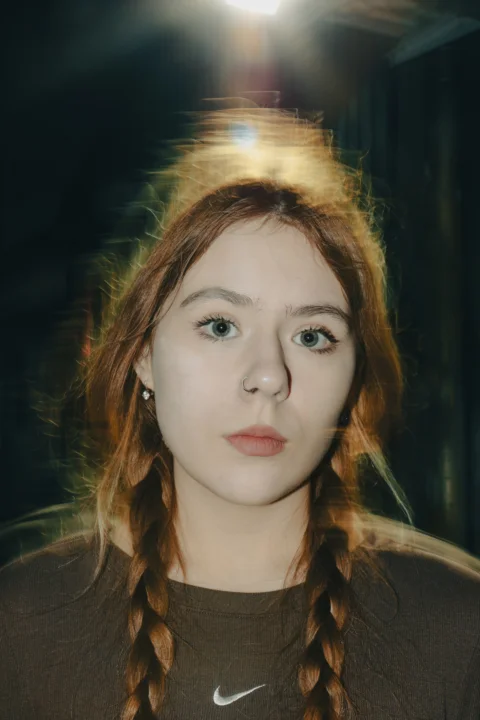 A woman with long red hair wearing a brown shirt