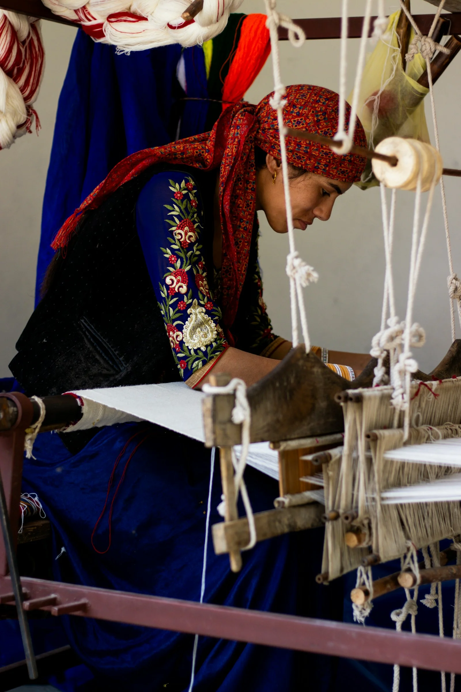 A woman is working on a weaving machine