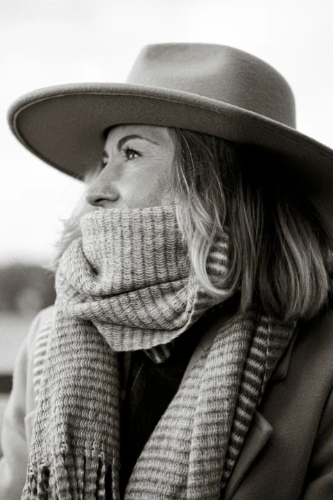A woman wearing a hat and scarf and a scarf around her neck