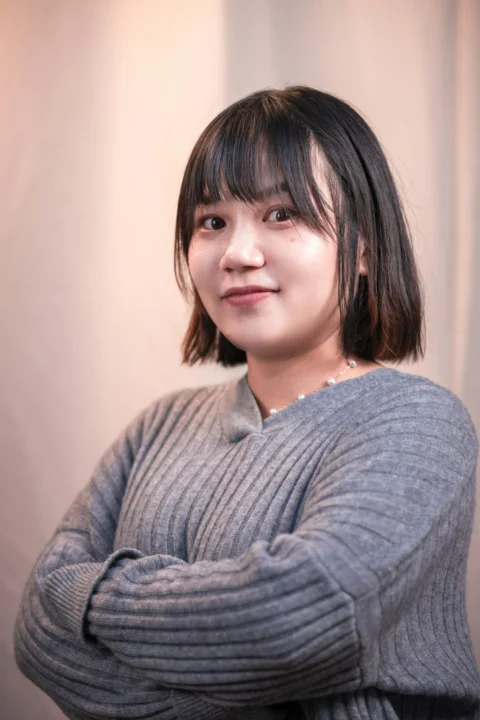 a woman in a gray sweater posing for a picture