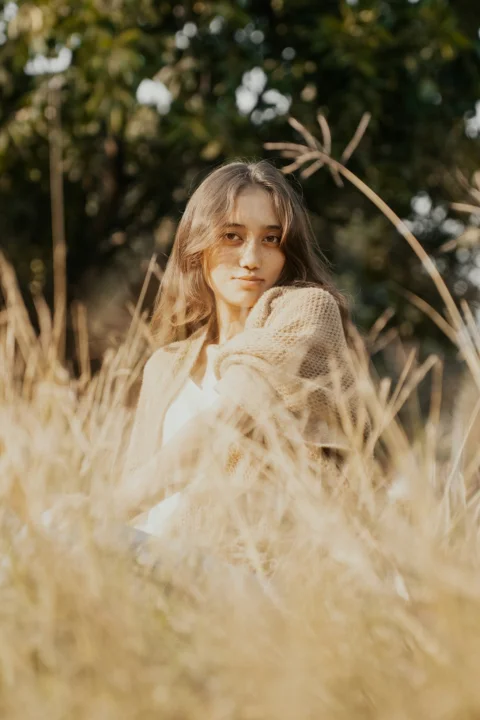 A woman sitting in a field of tall grass
