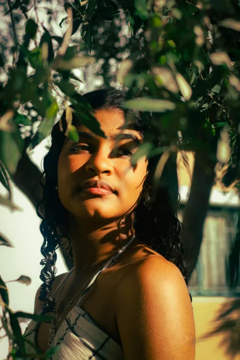 Young woman looking through olive tree branches