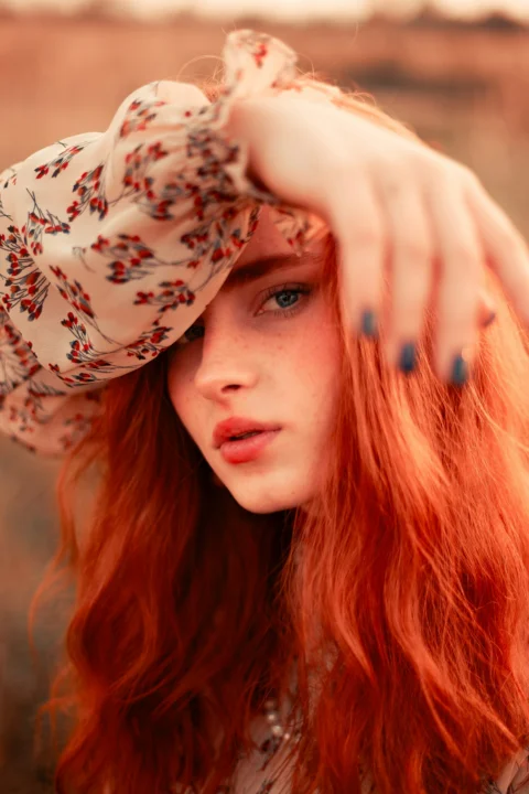 A woman with red hair wearing a hat