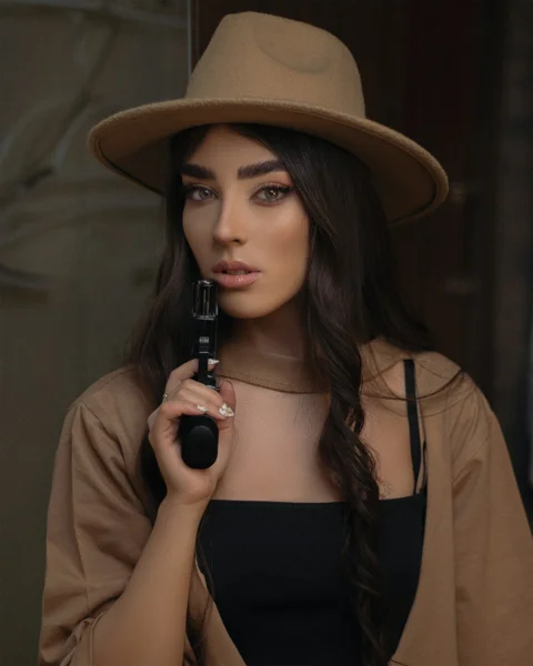 a woman wearing a brown hat holding a camera