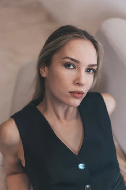 A woman in a black vest looks at the camera