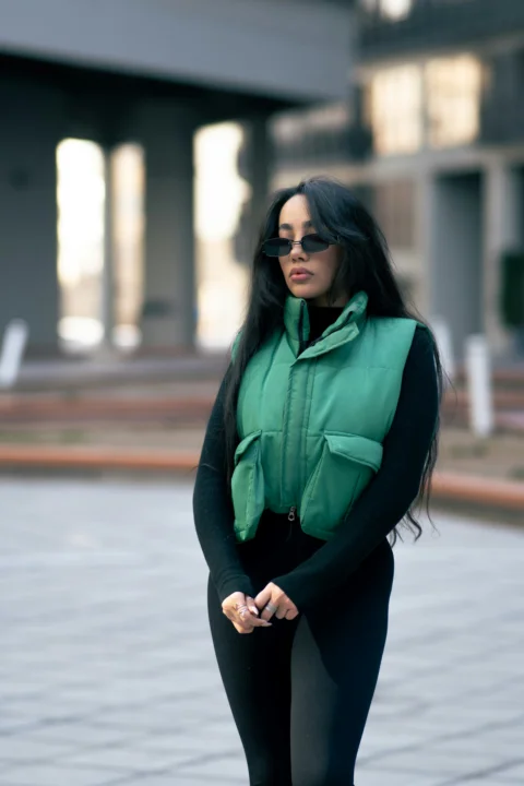 A stylish woman wears a green vest outdoors