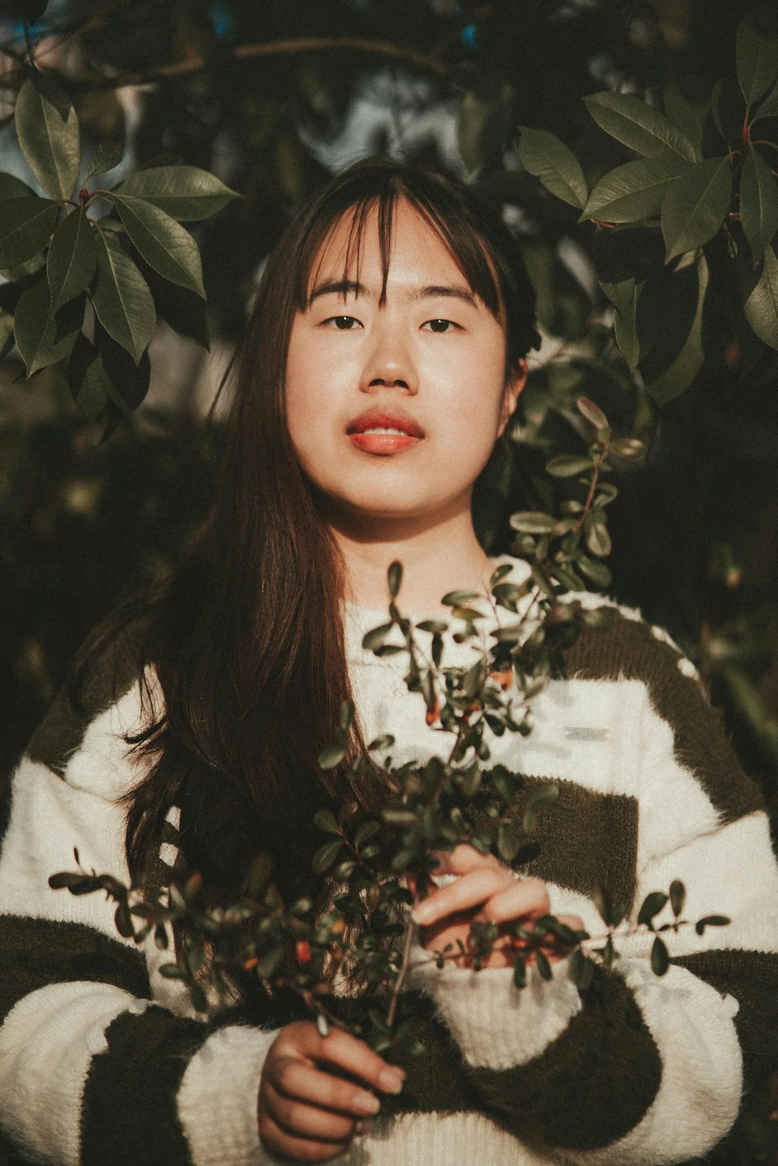 a woman standing under a tree holding a plant