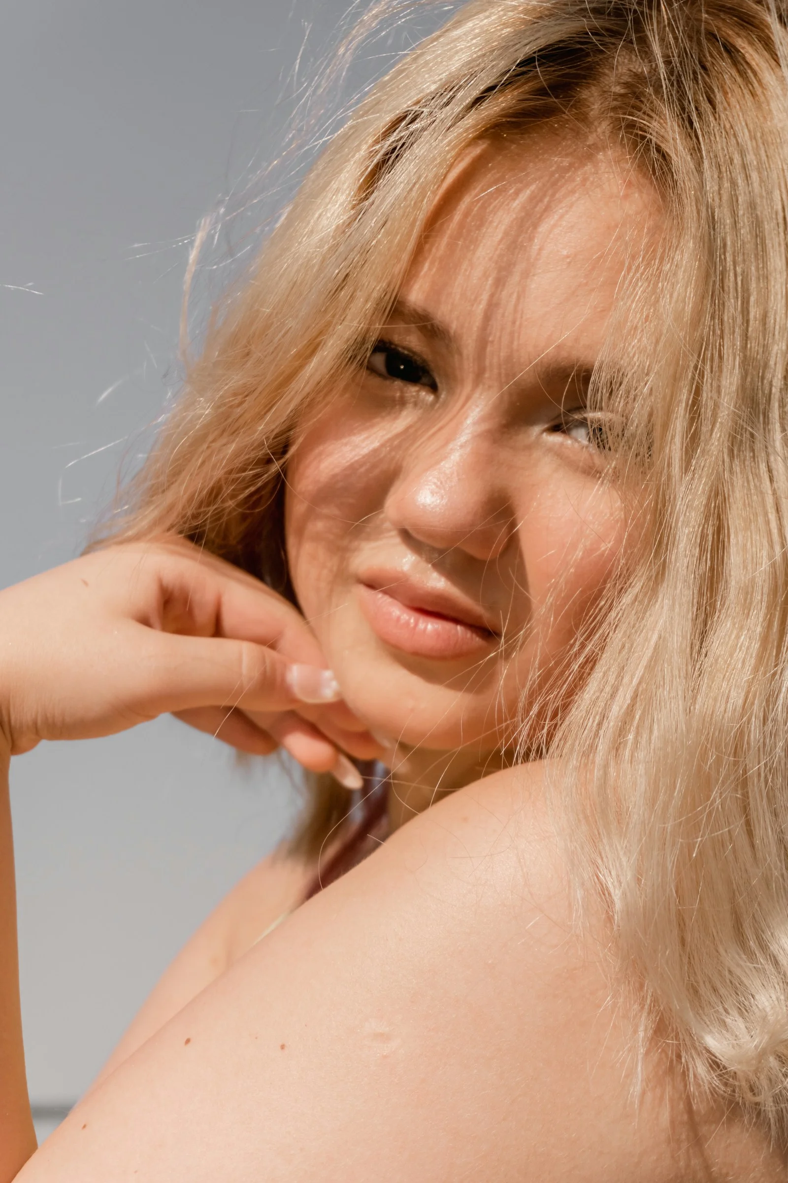 A young woman with blonde hair resting her chin on her hand