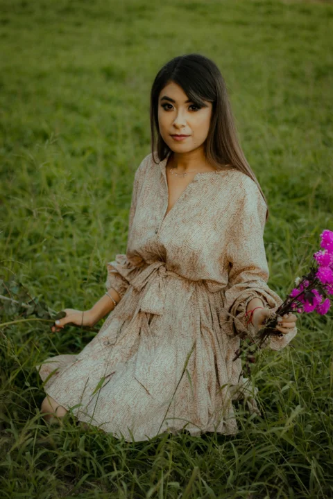 一位坐在田野中手拿紫色花朵的年轻女孩