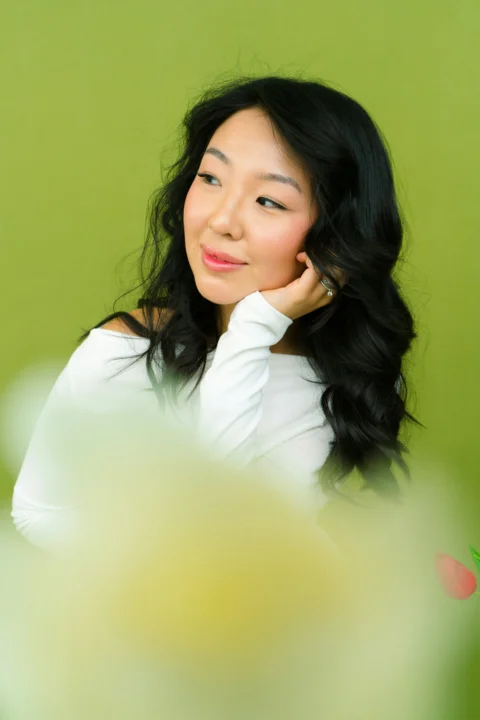 a woman is posing for a picture in front of a green wall