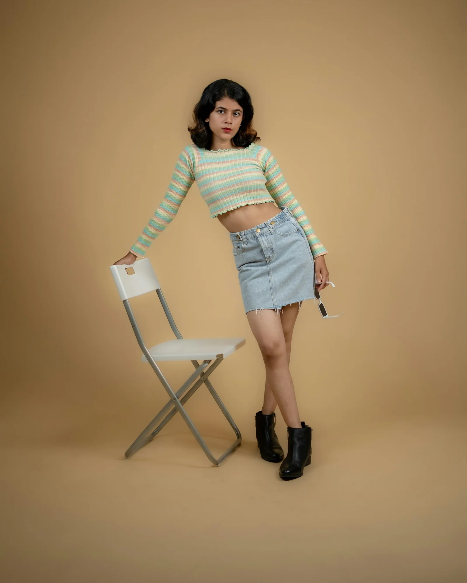 a woman standing next to a chair wearing a skirt