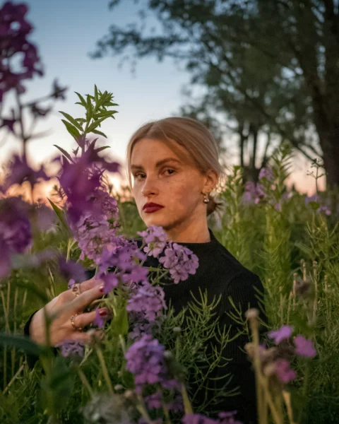 a woman standing in a field of purple flowers