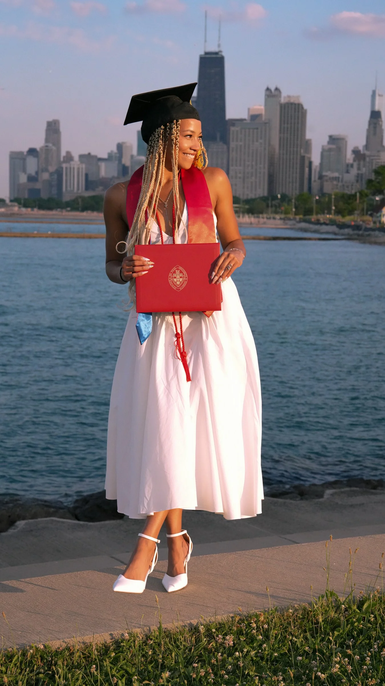 A woman in a graduation gown holding a laptop