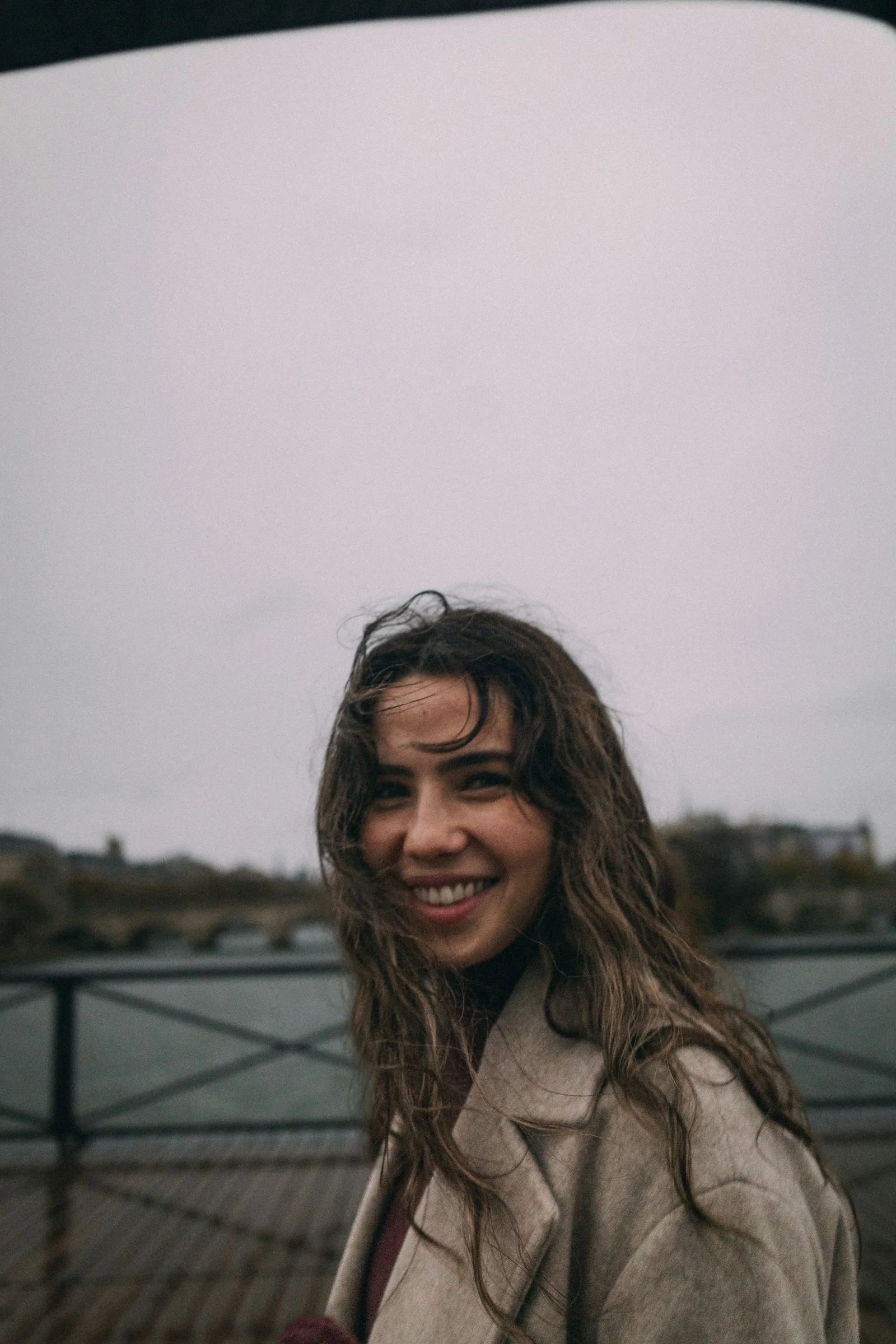Smiling woman with wavy hair against a cloudy sky