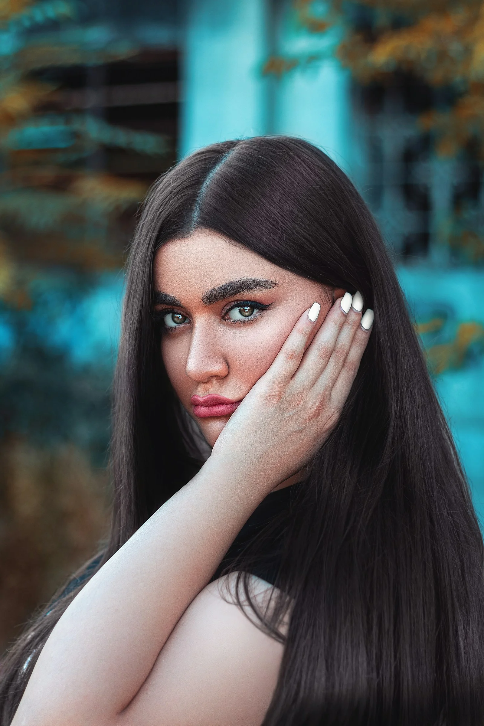 woman with black hair covering her face with her hand