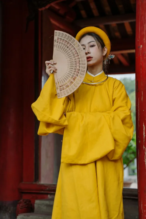 穿黃色服裝的女人拿著扇子