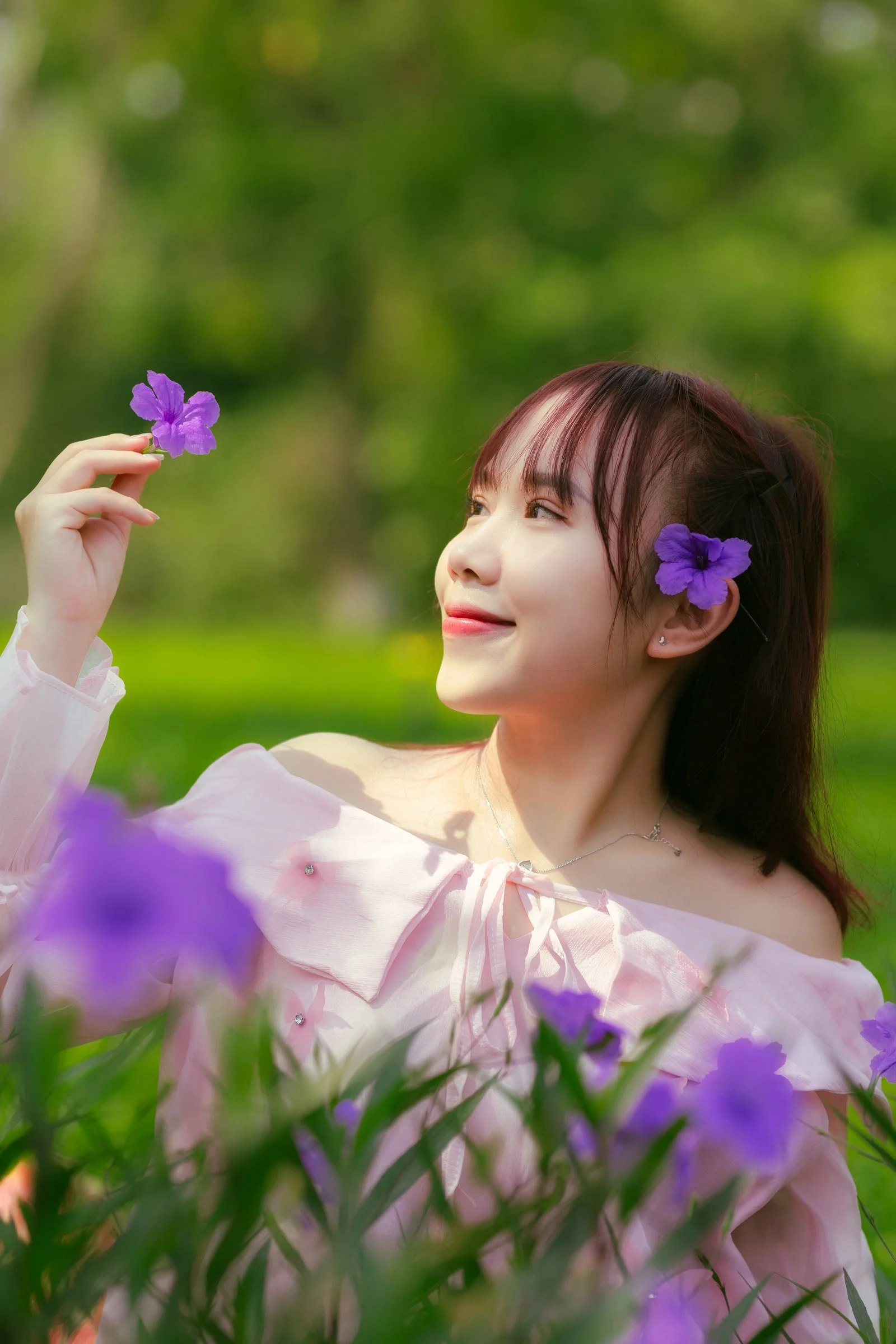 A woman in a pink dress holding a purple flower