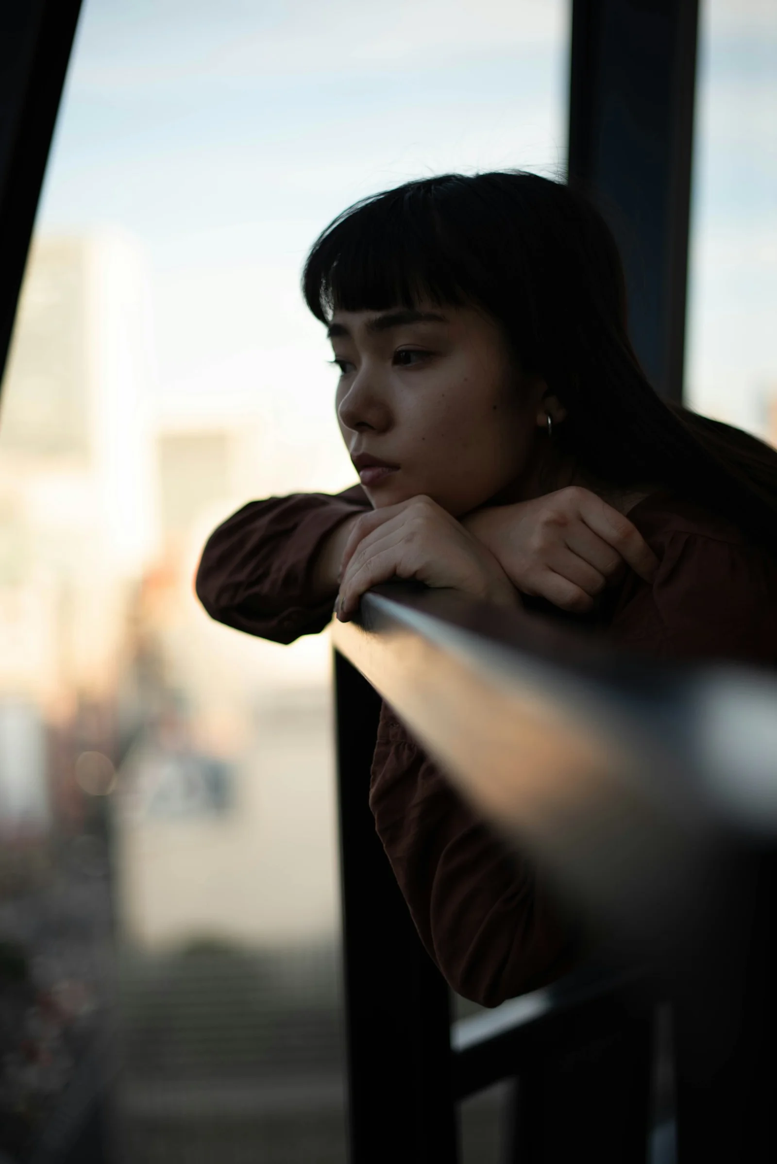 一位女子倚着栏杆望向窗外