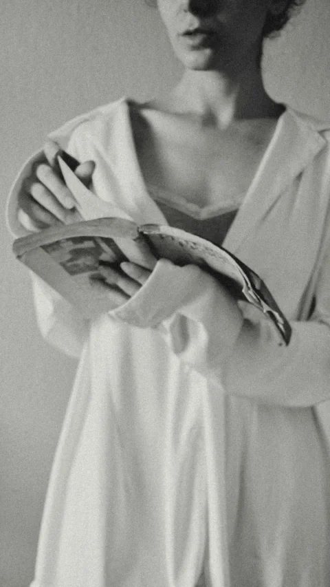 Woman in white shirt reading an open book