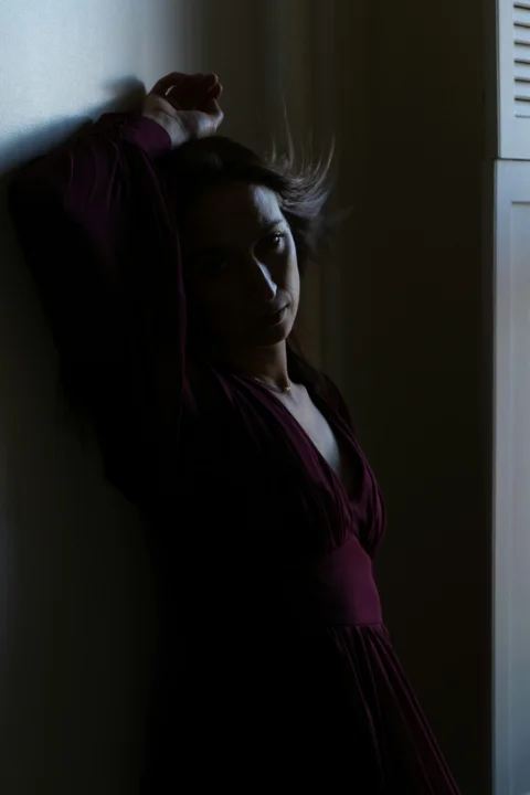 穿深色连衣裙的女子靠在墙上