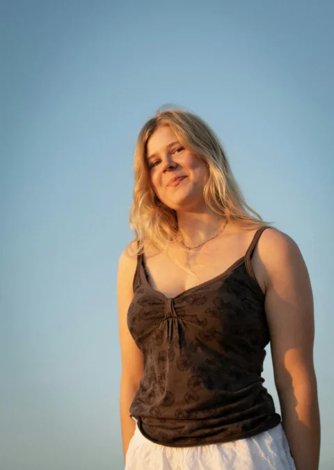 A young woman smiles against a clear sky