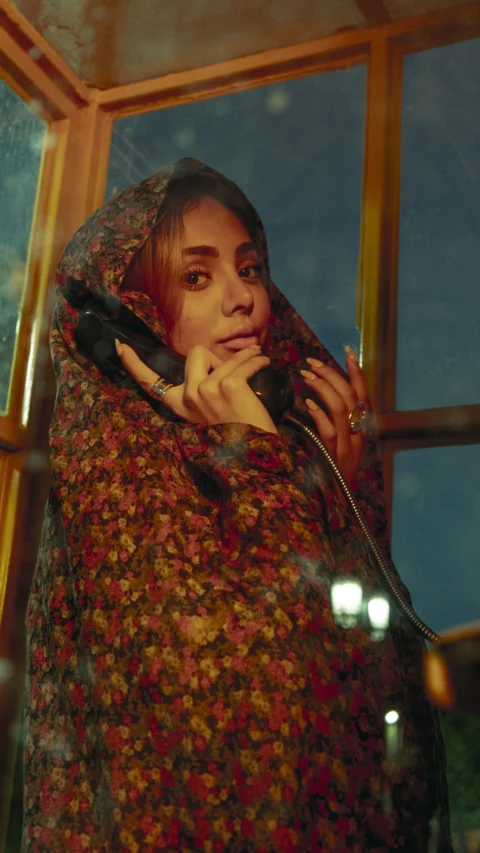 A woman in a phone booth is making a call