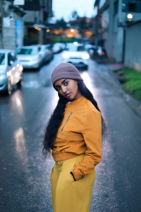 woman in brown jacket and gray knit cap standing on road during daytime