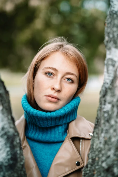 A woman with red hair looks between trees