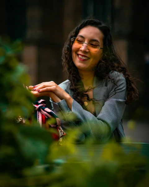 Young woman with curly hair smiling in orange sunglasses