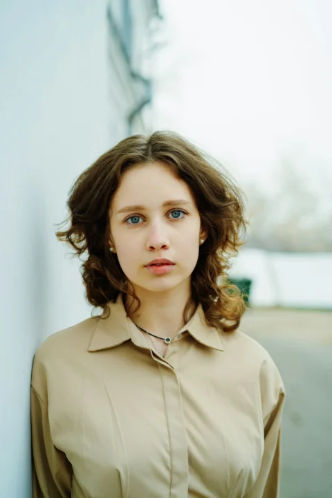 a woman standing next to a white wall