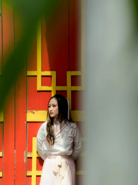 a woman standing in front of a red and yellow wall
