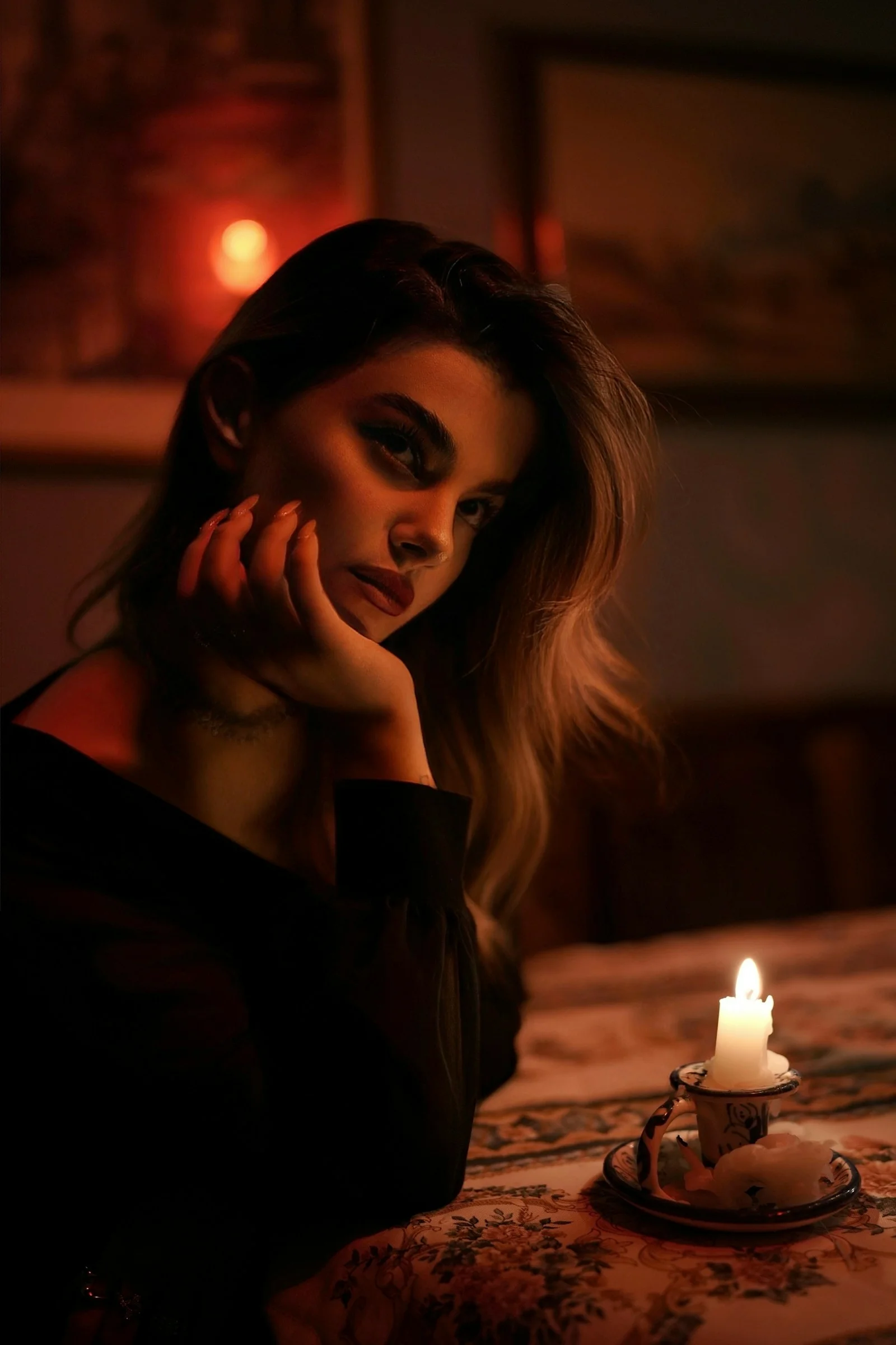 A woman with her hand on her chin beside a lit candle