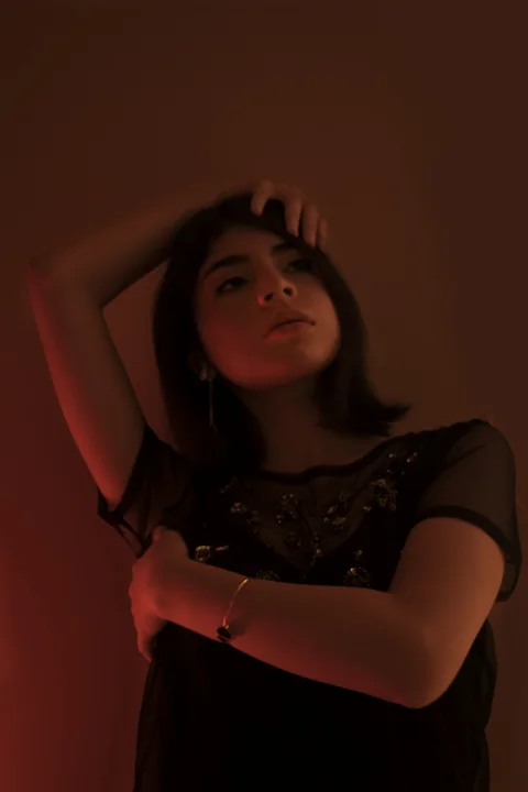 臉上映著紅光穿黑色襯衫的女子