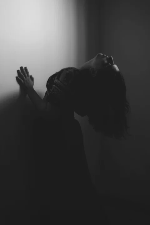 暗い部屋で両手を上げて立つ女性