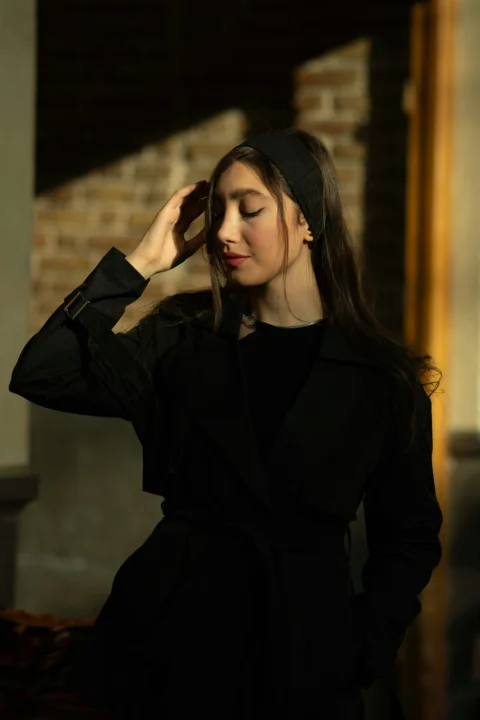 身穿黑色外套的年轻女士，手扶额头