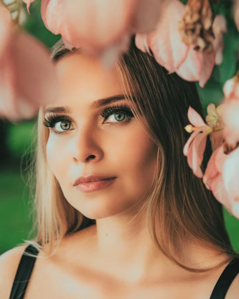 woman in black tank top holding pink flower during daytime